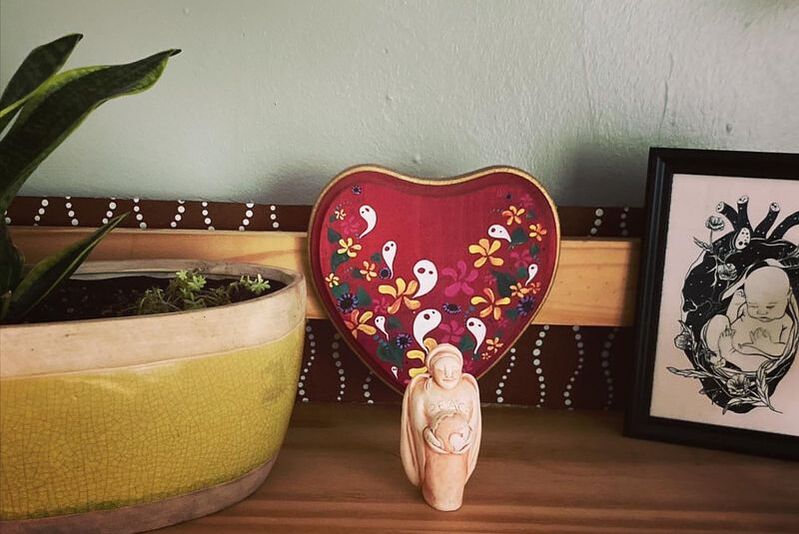 Image of a snake plant, a small terracotta sculpture, a heart-shaped piece of art, and an illustration of a baby.
